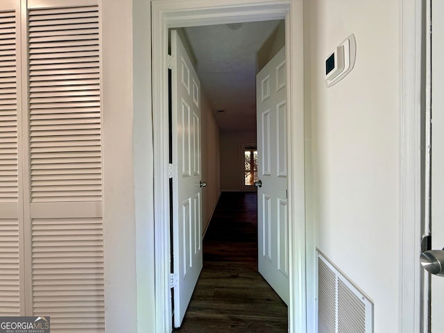 corridor featuring dark wood-style floors and visible vents