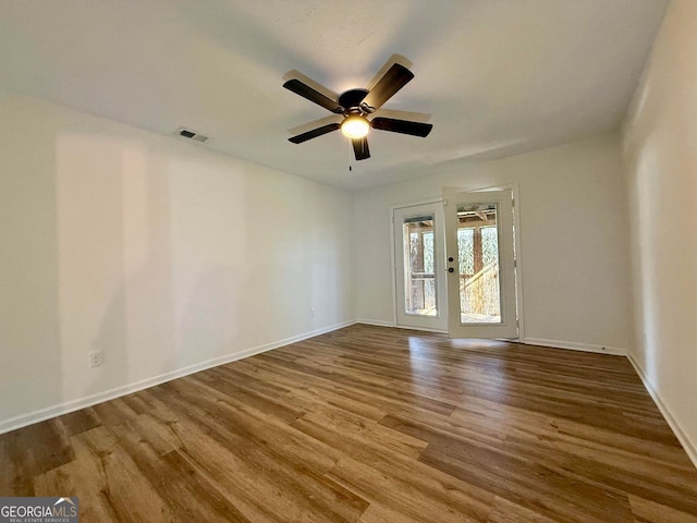 spare room with baseboards, visible vents, and wood finished floors