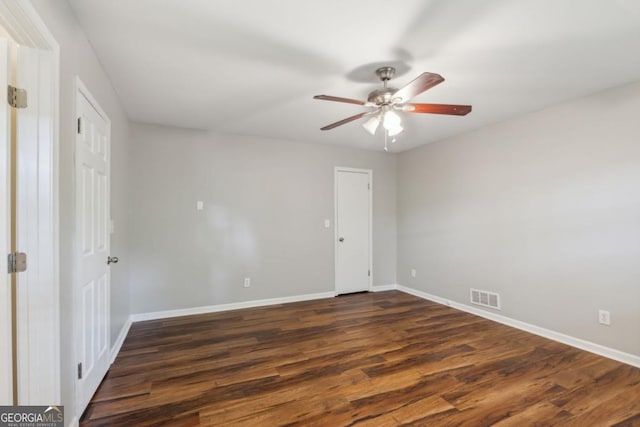 spare room featuring a ceiling fan, baseboards, visible vents, and dark wood-type flooring