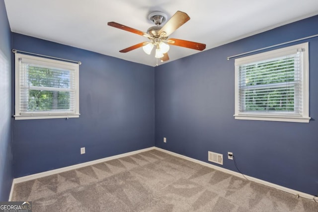 empty room featuring ceiling fan, carpet, visible vents, and baseboards