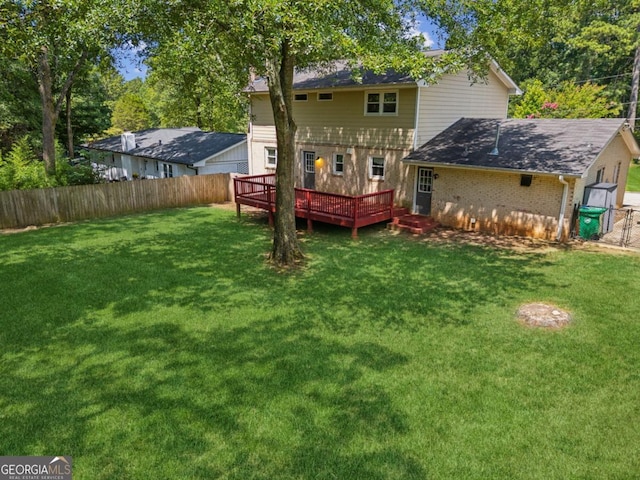 back of property featuring a fenced backyard, a yard, a wooden deck, and brick siding