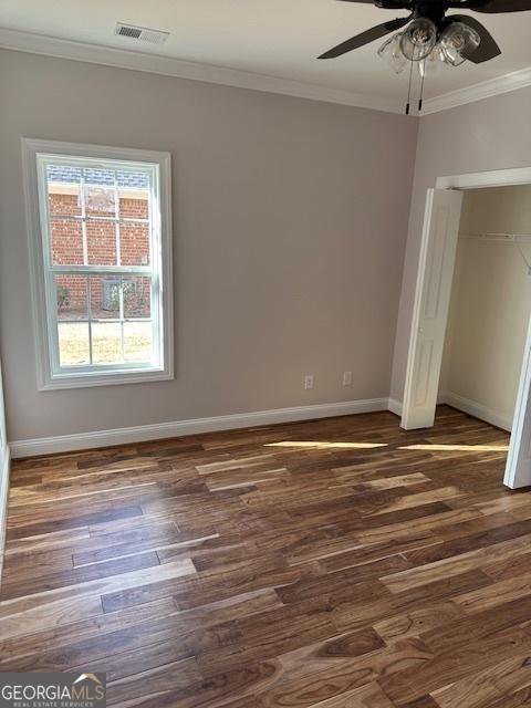 unfurnished bedroom featuring baseboards, visible vents, wood finished floors, crown molding, and a closet