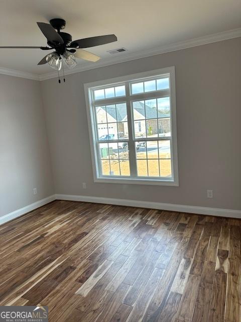 spare room featuring ornamental molding, dark wood-style flooring, and baseboards