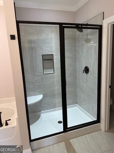 full bath featuring toilet, a shower stall, and crown molding