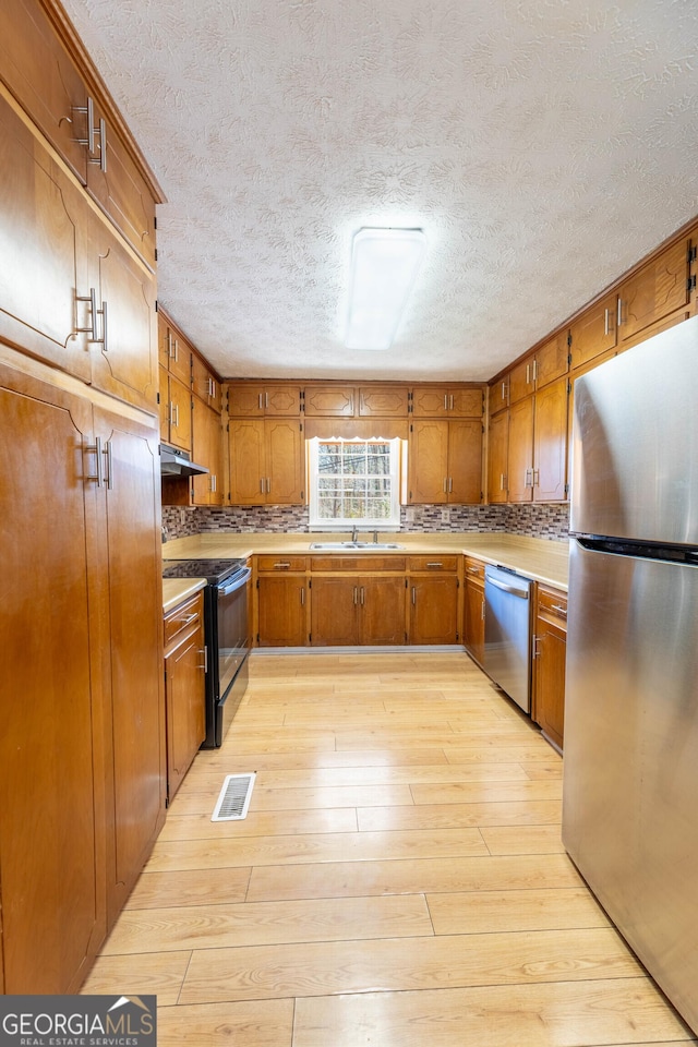 kitchen with visible vents, appliances with stainless steel finishes, brown cabinets, and a sink