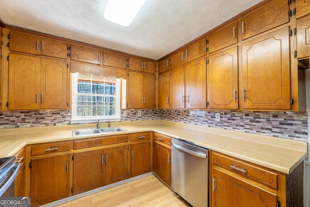 kitchen with light wood-type flooring, appliances with stainless steel finishes, brown cabinets, and a sink