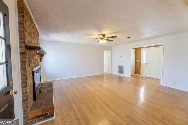 unfurnished living room with visible vents, ceiling fan, a textured ceiling, light wood-style floors, and a fireplace