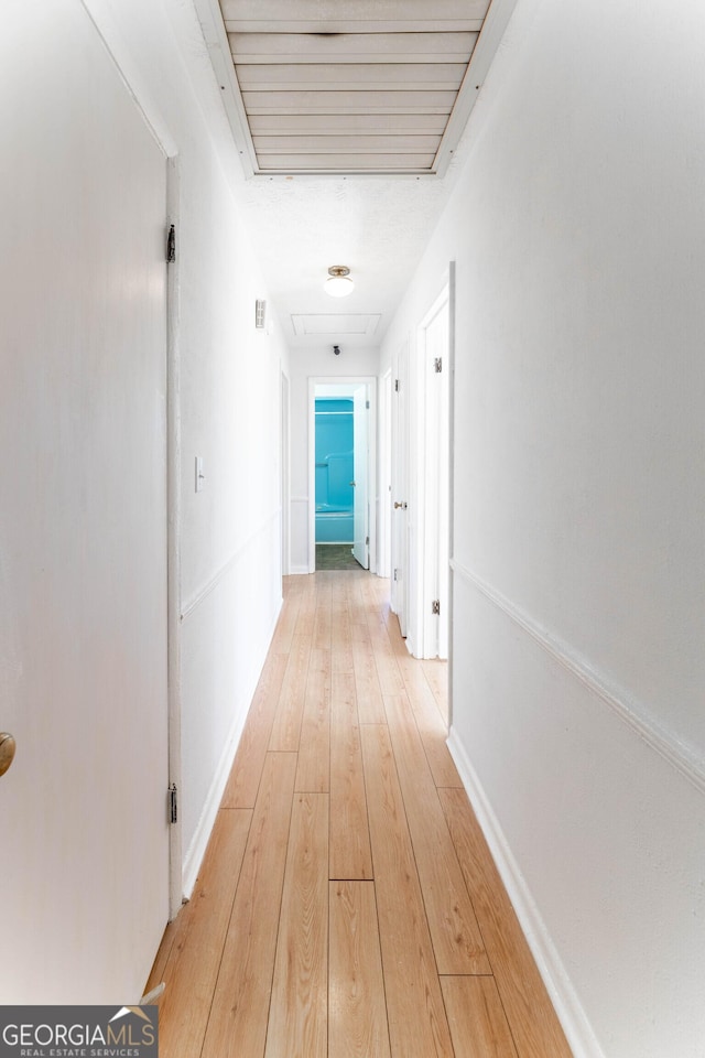 corridor with light wood-style flooring and baseboards