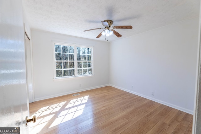 empty room with baseboards, visible vents, a ceiling fan, a textured ceiling, and light wood-type flooring