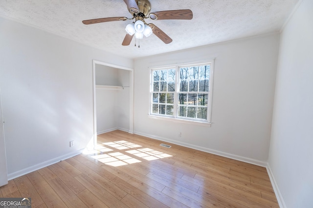 unfurnished bedroom with light wood-type flooring, a closet, visible vents, and a textured ceiling