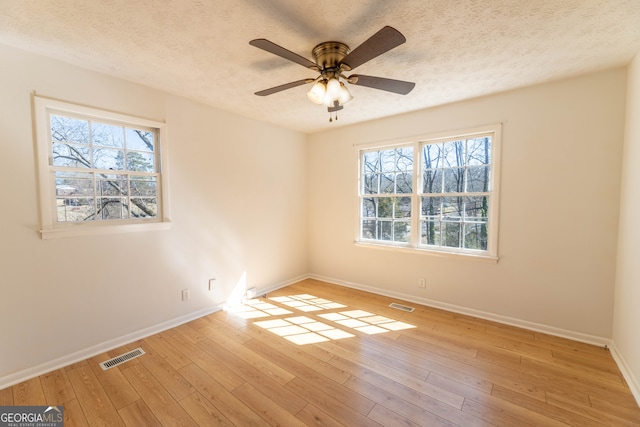 unfurnished room featuring a textured ceiling, wood-type flooring, and visible vents