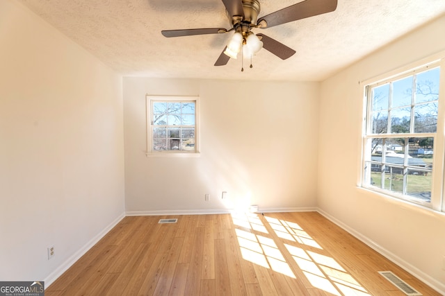 unfurnished room featuring light wood-style floors, plenty of natural light, and visible vents