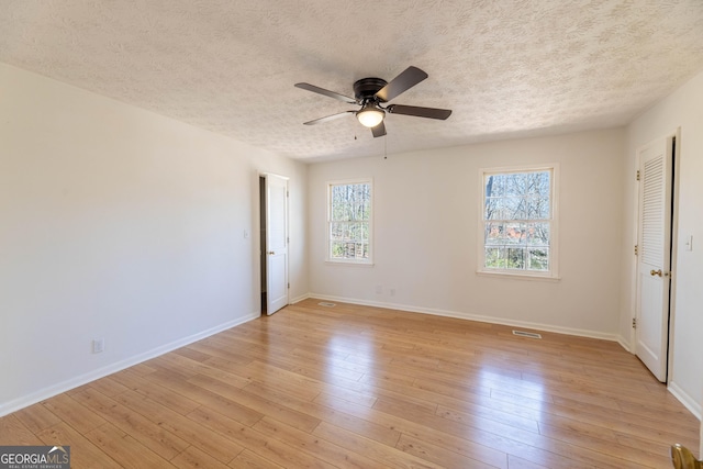 unfurnished bedroom featuring light wood finished floors, baseboards, and a textured ceiling