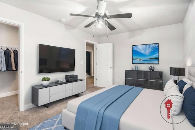 carpeted bedroom featuring a spacious closet, a closet, a ceiling fan, and baseboards