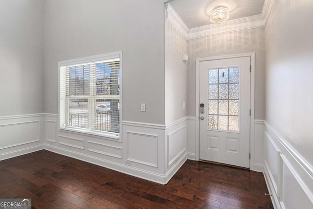 doorway to outside featuring dark wood-style floors, a decorative wall, wainscoting, and crown molding