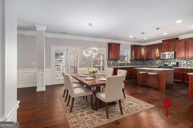 dining area featuring decorative columns, visible vents, dark wood-style flooring, and wainscoting