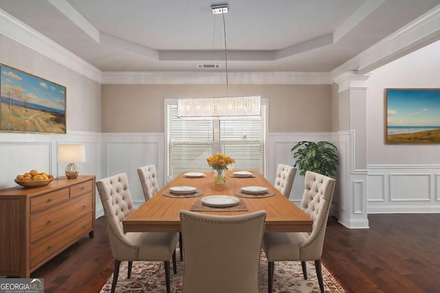 dining space featuring dark wood-style floors, a raised ceiling, visible vents, and ornate columns