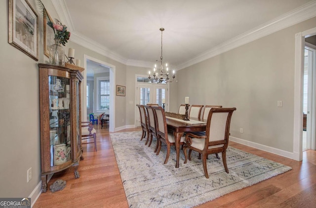 dining space with light wood-style floors, a notable chandelier, and crown molding