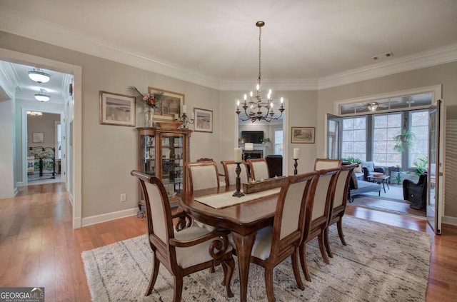 dining area with light wood-style flooring, a fireplace, and crown molding