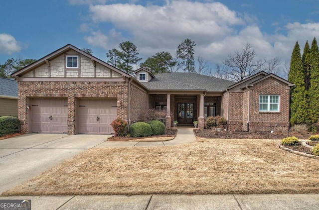 view of front facade with a garage, french doors, brick siding, and driveway