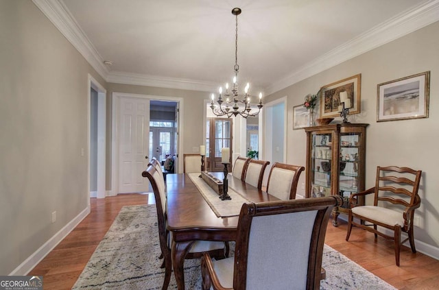 dining space featuring ornamental molding, an inviting chandelier, wood finished floors, and baseboards