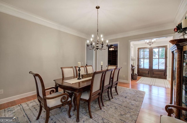 dining room with light wood-style floors, french doors, baseboards, and an inviting chandelier