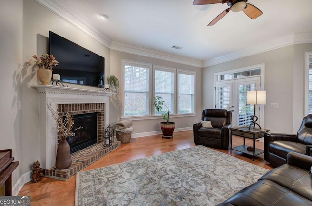 living area with ornamental molding, a healthy amount of sunlight, visible vents, and wood finished floors