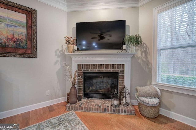 living area with baseboards, a brick fireplace, wood finished floors, and crown molding