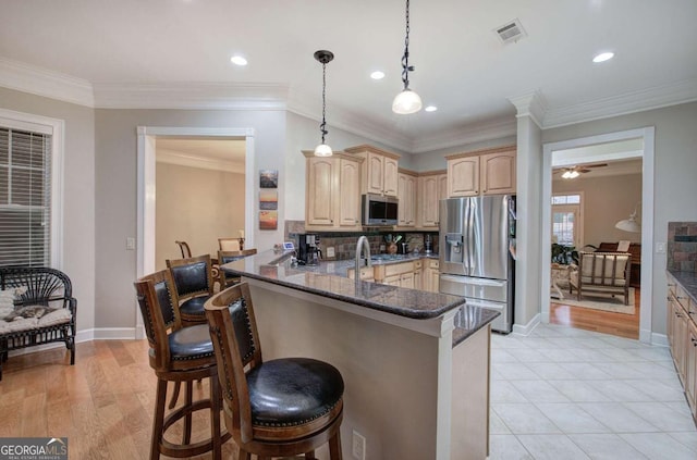 kitchen with visible vents, a breakfast bar, a peninsula, stainless steel appliances, and light brown cabinets