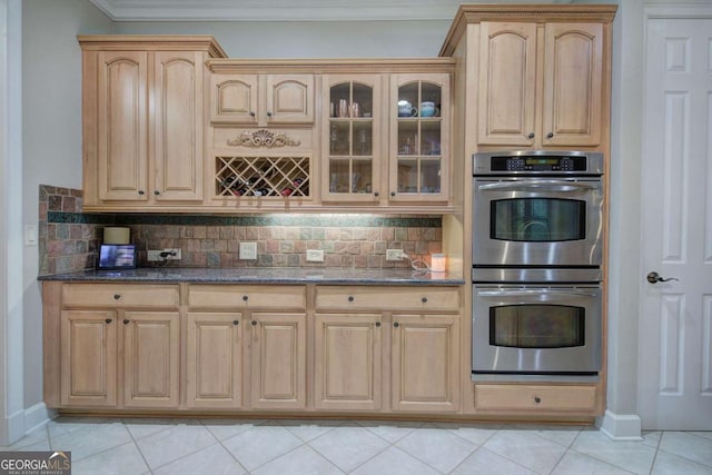 kitchen with dark stone counters, double oven, and backsplash