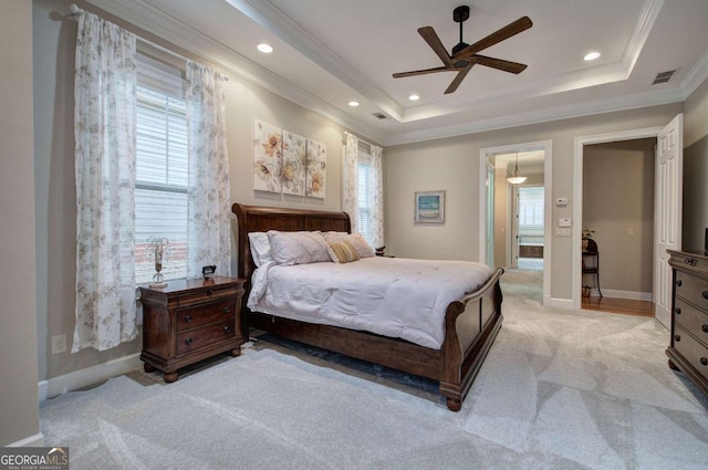 bedroom with multiple windows, a raised ceiling, visible vents, and light colored carpet