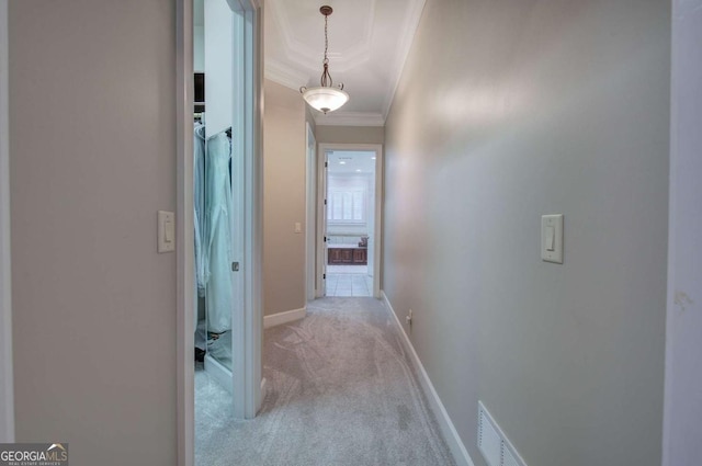 hallway featuring baseboards, visible vents, crown molding, and carpet flooring