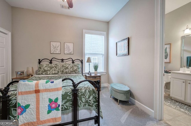 bedroom with visible vents, ensuite bath, light colored carpet, and baseboards