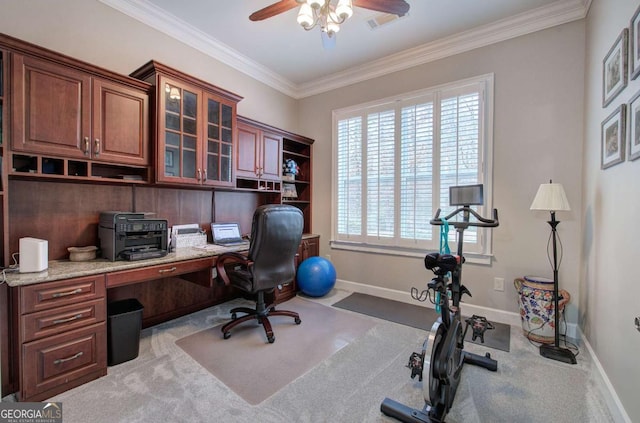 carpeted office with ornamental molding, built in study area, a ceiling fan, and baseboards