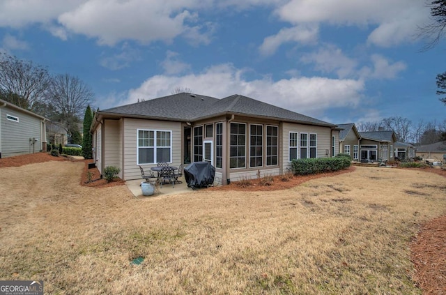 rear view of house featuring roof with shingles, a lawn, and a patio area