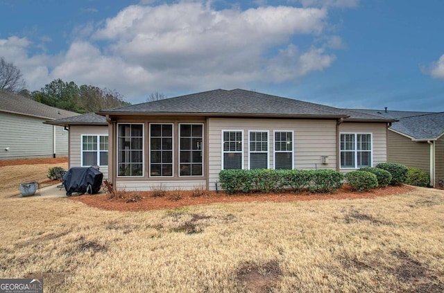 back of house featuring a shingled roof and a yard