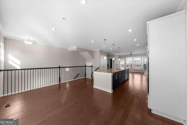 kitchen featuring recessed lighting, open floor plan, an island with sink, dark wood finished floors, and pendant lighting