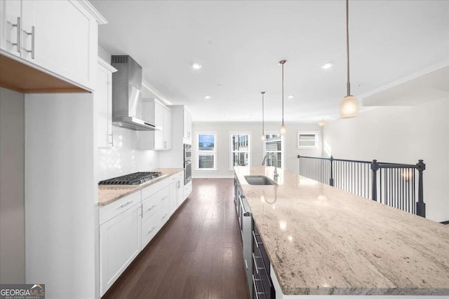 kitchen with stainless steel appliances, a sink, white cabinetry, a large island, and wall chimney exhaust hood