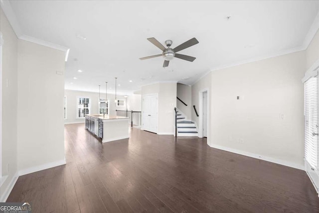 unfurnished living room with baseboards, stairway, dark wood finished floors, and crown molding