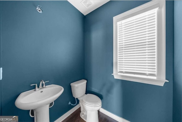 half bathroom featuring visible vents, toilet, a sink, wood finished floors, and baseboards