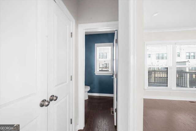 corridor featuring dark wood-style floors, baseboards, and crown molding