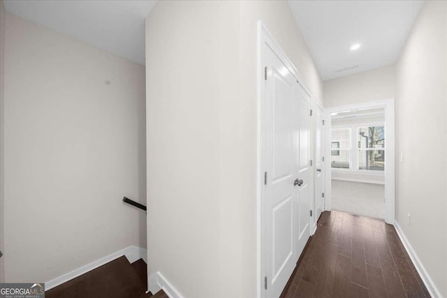 corridor with dark wood-style flooring, baseboards, and an upstairs landing