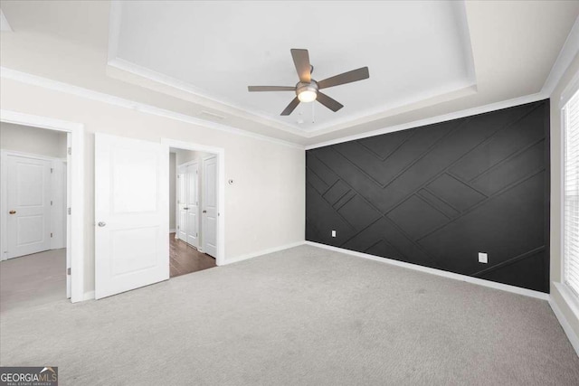 interior space featuring an accent wall, carpet, and a raised ceiling