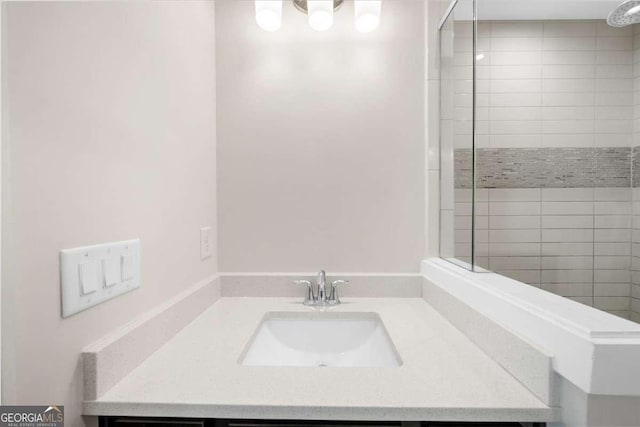 bathroom with a tile shower and vanity