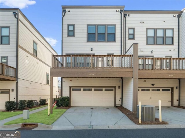 back of property with a garage, concrete driveway, and central air condition unit