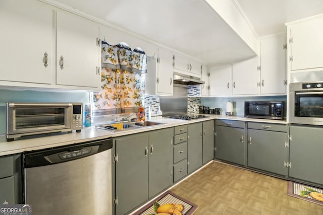 kitchen featuring a toaster, under cabinet range hood, a sink, appliances with stainless steel finishes, and crown molding