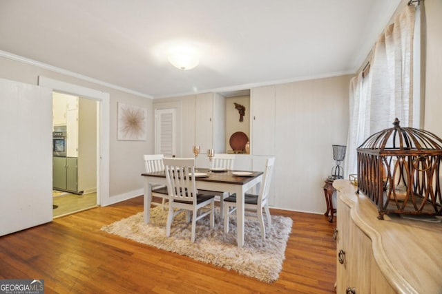 dining area with wood finished floors and crown molding