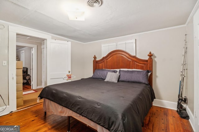 bedroom with visible vents, crown molding, baseboards, and hardwood / wood-style flooring