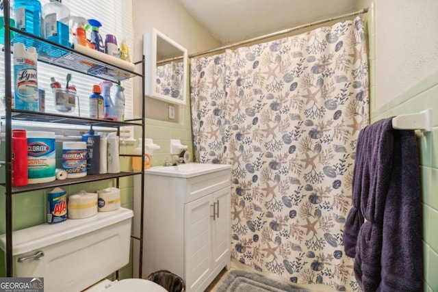 bathroom featuring wainscoting, toilet, a shower with shower curtain, vanity, and tile walls