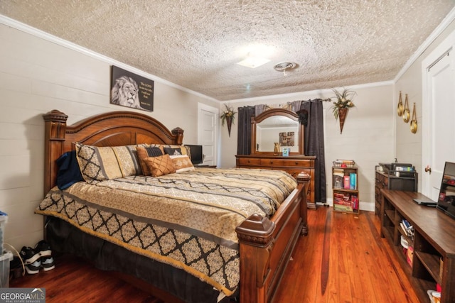 bedroom with ornamental molding, concrete block wall, a textured ceiling, and wood finished floors